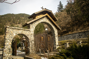 Stone gateway, entrance to the church yard. Mountain, forest, stone, Sunrise in cold winter day. Bele Vode in Serbia between Tara and Zlatibor mountain.