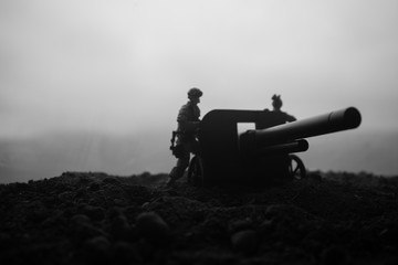 Battle scene. Silhouette of old field gun standing at field ready to fire. With colorful dark foggy background. Selective focus