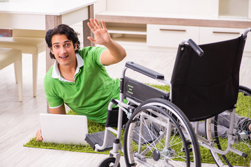 Young handsome man in wheelchair at home 