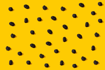 Top view of picked blackberries on yellow backgrond. Blackberry summer background, flat lay pattern.