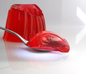 spoon full of sweet jelly pudding strawberry flavor over white background