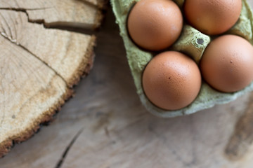 Closeup of raw chicken eggs in egg box on brown wooden background