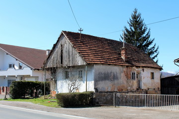 Small dilapidated family house made of wood and concrete abandoned by owners with cracked facade...