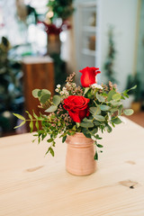 Red Roses bouquet in a pink vase on a wooden table. Florist