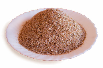 Wheat bran are in a saucer. Isolated on white background.