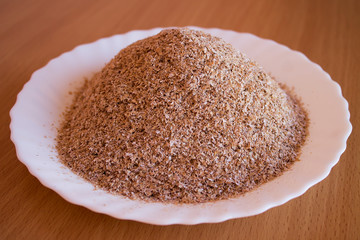 Wheat bran are in a white saucer on the kitchen table.