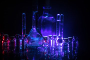 Pharmacy and chemistry theme. Test glass flask with solution in research laboratory. Science and medical background. Laboratory test tubes on dark toned background