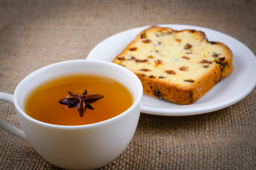 A cup of green tea with an anise-star and a delicious piece of cake