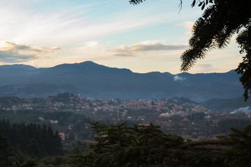 Mountainous greek village during winter with some clouds and a fir tree branch in the foreground
