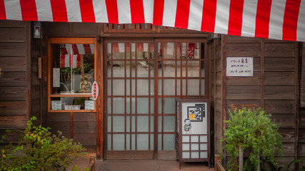 The entrance of a typical Edo-style shop with red and white banner normally seen in the castle town of Kawagoe which is now a famous tourist destination.
