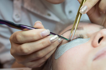 Beauty and fashion concept - Eye lash extension procedure. Young beautiful woman eye with long false eyelashes. Close up macro shot of fashion eyes in beauty salon.