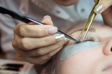 Beauty and fashion concept - Eye lash extension procedure. Young beautiful woman eye with long false eyelashes. Close up macro shot of fashion eyes in beauty salon.