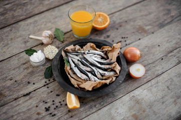 View from above on the fresh anchovies on plate with on a baking paper with a food around