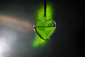 Valentines Day Concept. Glass transparent heart on dark. Crystal heart in the dark, glass heart glows, glass painting, black background