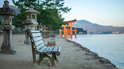 Distant landscape photo of the famous torii gate of Itsukushima Shrine floating in the sea in the...