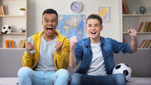 Afro-American and Caucasian friends cheering for favorite football team, hobby