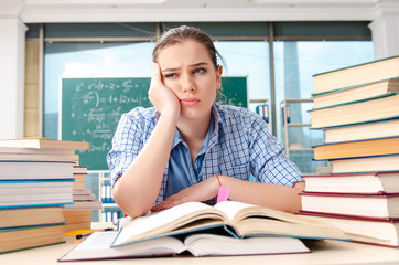 Female student with many books sitting in the classroom
