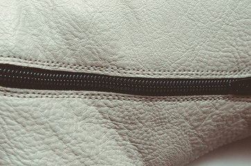 white leather with a lock, part of the zipper, leather background