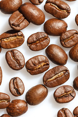 Roasted coffee beans on white can be used as background or texture. Close up.
