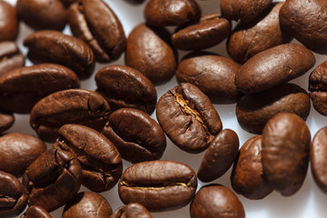 Roasted coffee beans on white can be used as background or texture. Close up.