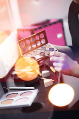 A young girl does make-up in a beauty salon. The girl in front of the mirror is making up. Beauty saloon.
