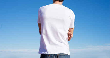 Photo of a man wearing white t-shirt. Blue sky on background