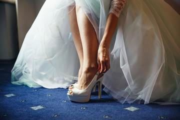 Fototapeta na wymiar Bride puts on white shoes in preparation for the wedding