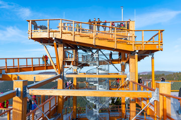 Tourists watching nature and walking on a new wooden lookout tower or sky walking in trees in Pustevny, Beskids, Czech Republic
