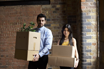 Portrait of male and female co-workers moving in to a new office