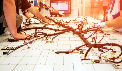 Hands of employees who check the quality of the wiring for cars at a modern plant on a special...