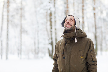 Fototapeta na wymiar Waist up portrait of bearded man in winter forest having fun and enjoying snow, copy space