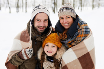 Portrait of happy family in winter forest looking at camera and smiling, copy space