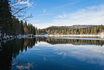 Mountain range Mangart seen from snow covert frozen lake Fusine with sunbeam