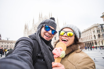 Travel in winter and relationship concept - Funny couple taking self portrait with ice-cream in Duomo square.