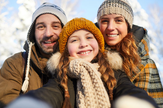 Closeup portrait of happy family posing looking at camera in beautiful winter forest