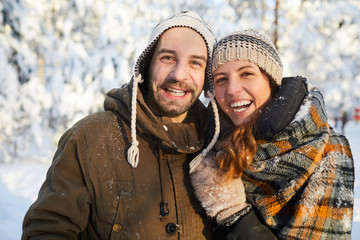 Waist up portrait of happy adult couple having fun in winter forest  and smiling, copy space