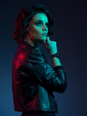 Thoughtful female studio portrait in neon light