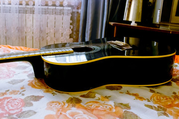 Acoustic guitar laying on bed low angle shot from bottom with plectrum on the body