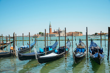 Fototapeta na wymiar Gondolas moored by Saint Mark square with San Giorgio di Maggiore church in Venice, Italy
