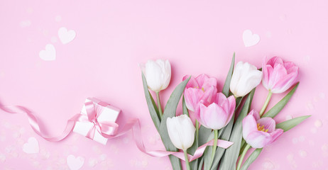 Gift box and beautiful spring tulip flowers on pastel pink background. Banner for Women Day, Mother day. Flat lay.