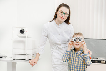 Pediatric Doctor ophthalmologist checks vision of child boy. Concept selection of glasses lenses.