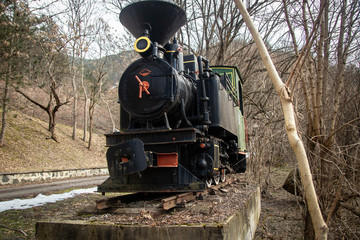 Old small steam locomotive on part of railway in the forest like a monument and tourist attraction 