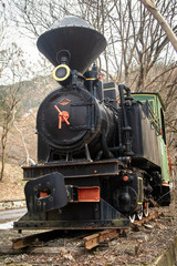 Old small steam locomotive on part of railway in the forest like a monument and tourist attraction 