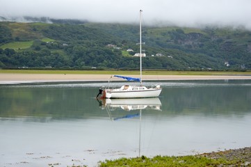 Boat on a still calm lake on a dull misty day.