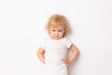 portrait of cute caucasian smiling curly baby girl in dirty white clothes t-shirt on white background.