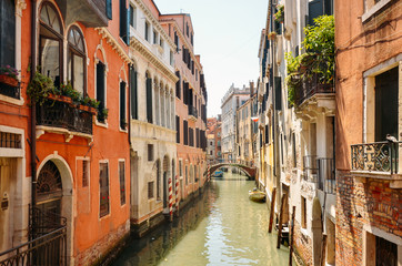 Fototapeta na wymiar Narrow canal with boat and bridge in Venice, Italy. Architecture and landmark of Venice. Cozy cityscape of Venice