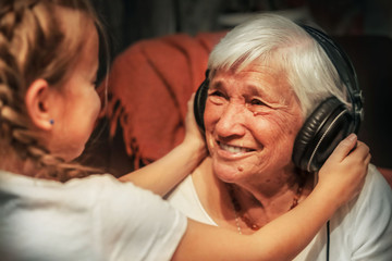 old woman and little girl in headphones listening to music grandmother and granddaughter