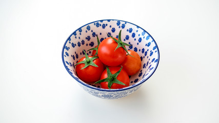 Pomidorki koktajlowe leżące w misce na białym tle