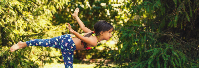 Naklejka na ściany i meble Pretty little girl doing exercises in the summer park