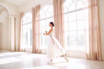 Fototapeta na wymiar Young ballerina dancing in a white studio